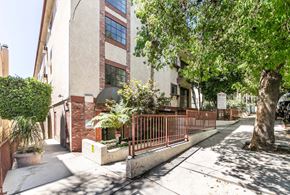 Hollywood multi-family for rent - Tree lined walkway with residential building and fencing at Joro Properties Apartments, California, 90046