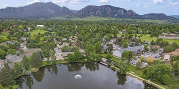 Boulder apartment for rent - A serene lake surrounded by houses and trees with mountains in the distance.