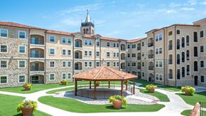 Mckinney apartment for rent - The cabana in the courtyard of Bell Tower Reserve, the apartment building surrounding it behind on a sunny day.