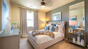 Mckinney apartment for rent - A bedroom in a residence at Bell Tower Reserve. A dresser is on the left, a window ahead and the bed is on the right. A ceiling fans spins above.