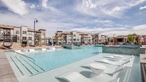 Centennial apartment for rent - Outdoor pool and lounge area at The Wright in Centennial, Colorado featuring in-water seating, modern landscaping, and contemporary apartment residences in the background.