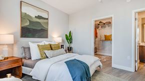 Centennial apartment for rent - Modern bedroom interior at The Wright featuring contemporary furnishings, wood-style flooring, a walk-in closet, and soft natural lighting.