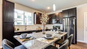 Phoenix apartment for rent - Modern kitchen with dark wood cabinets, stainless steel appliances, a marble countertop, and a dining area set for two.