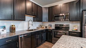 Phoenix apartment for rent - Modern kitchen with dark wood cabinets, stainless steel appliances, and granite countertops.