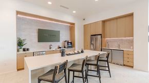 Aurora apartment for rent - Modern community kitchen and coffee bar at Tempo at Nine Mile featuring a large island, bar seating, stainless steel appliances, and contemporary cabinetry.
