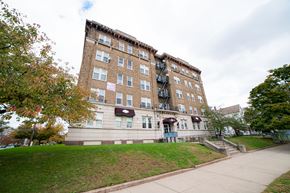 New Haven apartment for rent - A brown building with a red awning sits on a grassy hill.