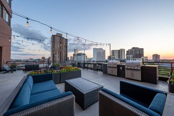 A rooftop patio with couches and a city skyline at dusk
