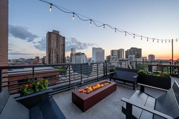 Elevate apartment homes rooftop deck with a fire pit and a city skyline at dusk