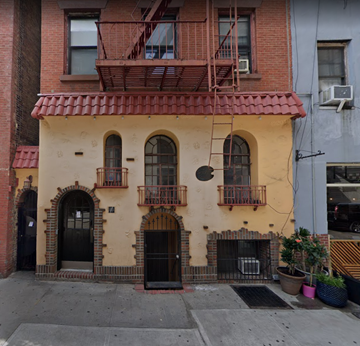 New York apartment for rent - the front of a building with a yellow facade and a balcony