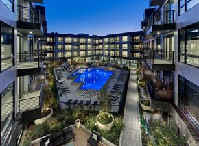 Orange apartment for rent - A swimming pool surrounded by balconies and potted plants.