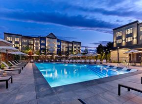 Hackettstown apartment for rent - A large swimming pool surrounded by lounge chairs and umbrellas in front of a hotel.