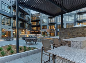 Paramus apartment for rent - A modern outdoor seating area with a stone wall and wooden furniture.