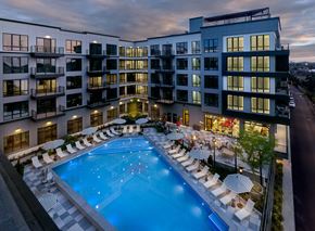 Belleville apartment for rent - A large swimming pool surrounded by lounge chairs and umbrellas is the focal point of the image.