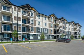 Sylvan Lake apartment for rent - A grey and white apartment building with a car parked in front.