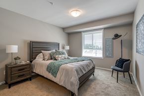 Sylvan Lake apartment for rent - A bedroom with a bed, nightstand, chair, and a window.