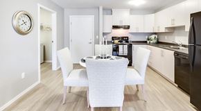 Saskatoon apartment for rent - A bright open kitchen, with light cabinets and black appliances. A round table sits in the middle with four chairs