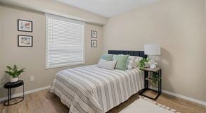 Calgary apartment for rent - A bedroom with a bed, small nightstand and large window