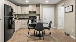 Calgary apartment for rent - A bright open kitchen with light cabinets and black appliances with a round table in the centre