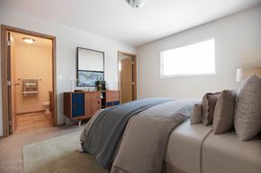 Winnipeg apartment for rent - A bedroom with a bed, nightstand, and a window.