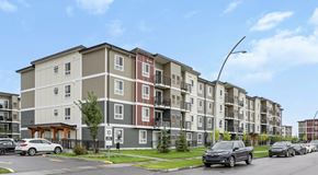 Saskatoon apartment for rent - Apartment building with cars parked in front. and a parking lot to the side of the building