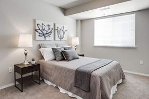 Red Deer apartment for rent - A bedroom with a bed, two lamps, and two paintings on the wall.