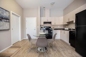 Saskatoon apartment for rent - A kitchen with a black fridge, white cabinets, and a table with four chairs.