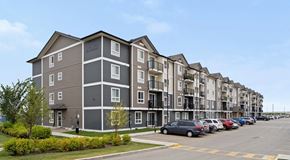 Saskatoon apartment for rent - Apartment building with grey and white exterior and a parking lot in front.