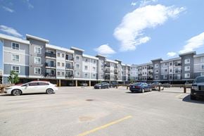 Winnipeg apartment for rent - A parking lot with cars and apartment buildings in the background.