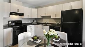 West Kelowna townhouse for rent - Apartment kitchen with light cabinets and black appliances a kitchen table sits in the centre