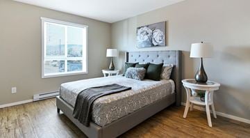 West Kelowna townhouse for rent - A bedroom with a large bed and a window overlooking a parking lot.
