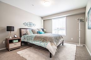 Red Deer apartment for rent - A bedroom with a bed, nightstand, and lamp.
