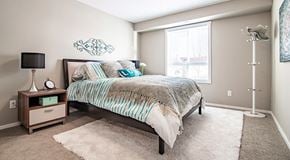 Red Deer apartment for rent - A bedroom with a queen sized bed and night stands. A large window with blinds