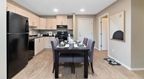 St. Albert apartment for rent - A kitchen with light cabinets and black appliances, a rectangular table sits in the centre