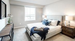 Penticton apartment for rent - A bedroom with a queen sized bed, nightstands, and a window.