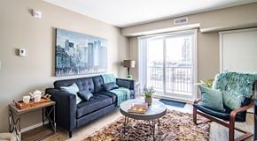 Red Deer apartment for rent - A living room with couch, end table, chair and coffee table. A large glass sliding door leading to a blacony