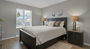 Courtenay apartment for rent - A bedroom with a large bed, a nightstand with a lamp, and a window with blinds.