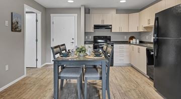 Courtenay apartment for rent - A kitchen with a black refrigerator, a dining table with chairs and a countertop with a sink.