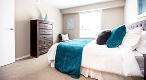 Penticton apartment for rent - A bedroom with a large bed, dresser and large window