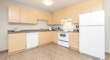 Winnipeg apartment for rent - A kitchen with wooden cabinets and white appliances.