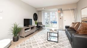Winnipeg apartment for rent - a spacious living room with couch, chairs, coffee table and tv with stand. Glass sliding door and utility closet