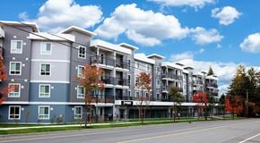 Comox apartment for rent - A row of modern apartment buildings with trees in autumn colors in front.