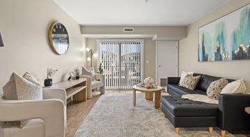 Chestermere apartment for rent - A living room with a large painting on the wall and a sofa with a black cushion.