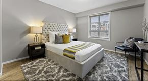 Calgary apartment for rent - A large room with bed, nightstands and chair with window