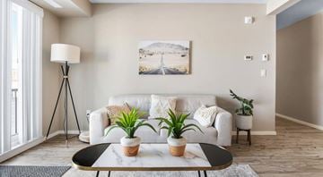 Lethbridge apartment for rent - A living room with a white couch, a black table, and a painting on the wall.