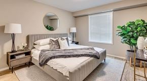 Calgary apartment for rent - A well-lit bedroom with a queen sized bed, night stands and large window