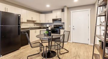 Calgary apartment for rent - A black refrigerator is in a kitchen with a table and chairs.