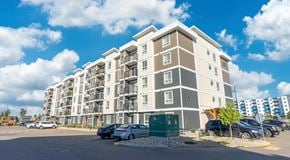Edmonton apartment for rent - A large apartment building with a parking lot in front.