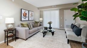 St. Albert apartment for rent - An open living room with couch, coffee table, end tables and chairs. Large glass sliding door on exterior wall