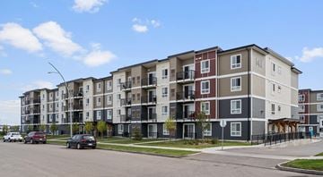 Saskatoon apartment for rent - A large apartment building with cars parked in front.