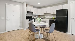 Warman apartment for rent - A kitchen with light cabinets and black appliances. A small pantry sits next to the fridge and a round kitchen table in the center of the room.